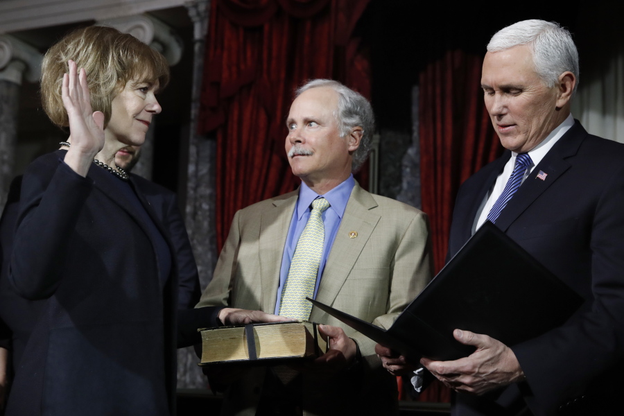 Vice President Mike Pence, right, administers the Senate oath of office during a mock swearing in ceremony in the Old Senate Chamber to Sen. Tina Smith, D-Minn., left, with her husband Archie Smith, center, on Wednesday on Capitol Hill in Washington. Sen. Smith will take over from Al Franken who resigned.