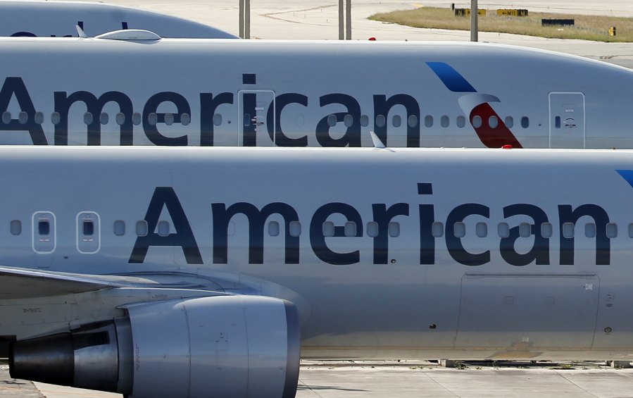 A pair of American Airlines jets are parked on the airport apron at Miami International Airport in Miami. Dozens of companies have announced they are giving their employees bonuses, following the passage of the Republican tax plan that President Donald Trump signed into law in December. American Airlines is handing out $1,000 bonuses to its employees.