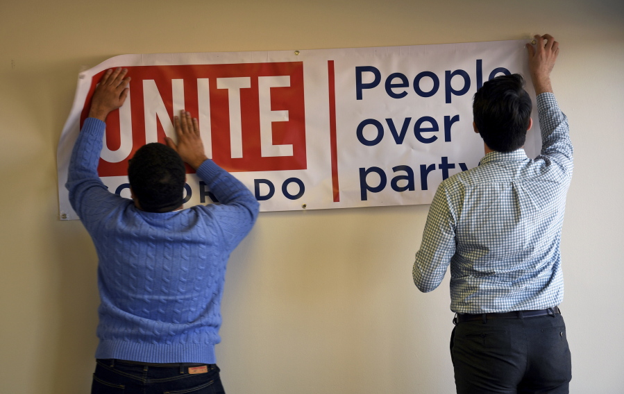 Dominick Scafidi, left, in charge of field and digital operations and Jake Wiegman, right, special projects manager put up a sign during a brainstorming session at the Unite America office in Denver. The constant fighting in Washington is giving new motivations to groups trying to lower the importance of partisanship in U.S. politics. Unite America is recruiting candidates to run as nonpartisans for various U.S. Senate and governors seats.