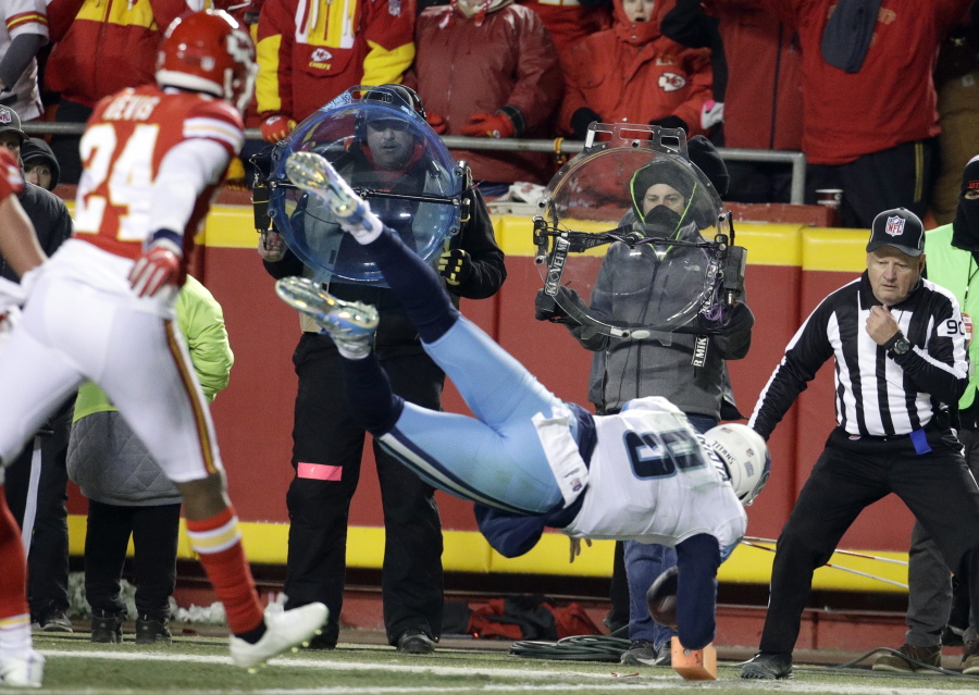 Tennessee Titans quarterback Marcus Mariota (8) leaps over the goal line for a touchdown in front of Kansas City Chiefs defensive back Will Redmond (24) during the second half of an NFL wild-card playoff football game in Kansas City, Mo., Saturday, Jan. 6, 2018.