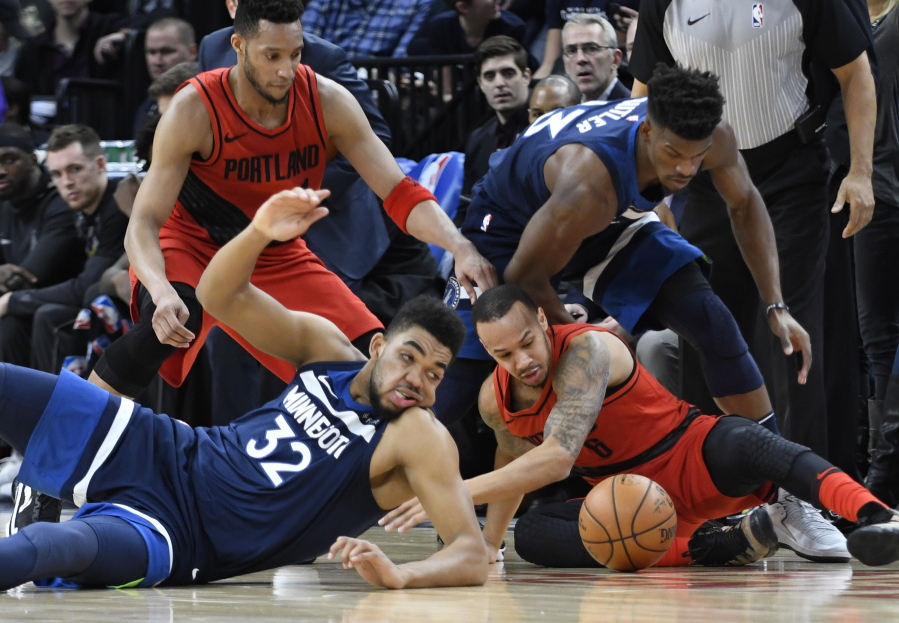 Minnesota Timberwolves’ Karl-Anthony Towns, front left, and the Portland Trail Blazers’ Damian Lillard, front right, go after the ball during the first half of an NBA basketball game Sunday, Jan. 14, 2018, in Minneapolis.