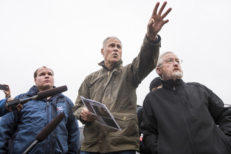 Gov. Jay Inslee speaks during a news conference Sunday as Jeff Emmons, director of Yakima Valley Office of Emergency Management, at left, and Washington state geologist Dave Norman listen near Union Gap. Dozens of residents in central Washington state need to evacuate due to a slow-moving landslide that’s expected to break loose by the end of February, authorities said.