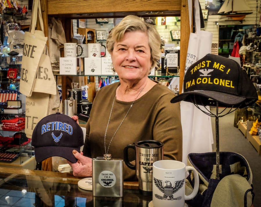 Mary Beth Cox, founder of the Ship’s Hatch in Crystal City, Va., shows some of the shop’s wares Jan. 10. The store sells military-inspired memorabilia, including ball caps and challenge coins. After more than 30 years running the business, Cox retired last week.