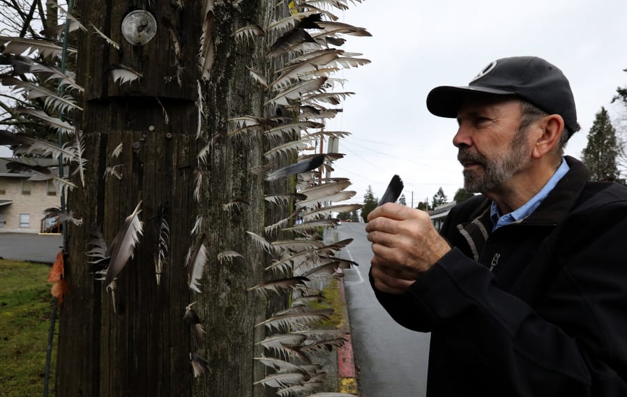 Jerry Gay, retired photographer living in Everett, collects pigeon feathers and a few from crows, for his “spontaneous art project” on an unused power pole on Madison Street.