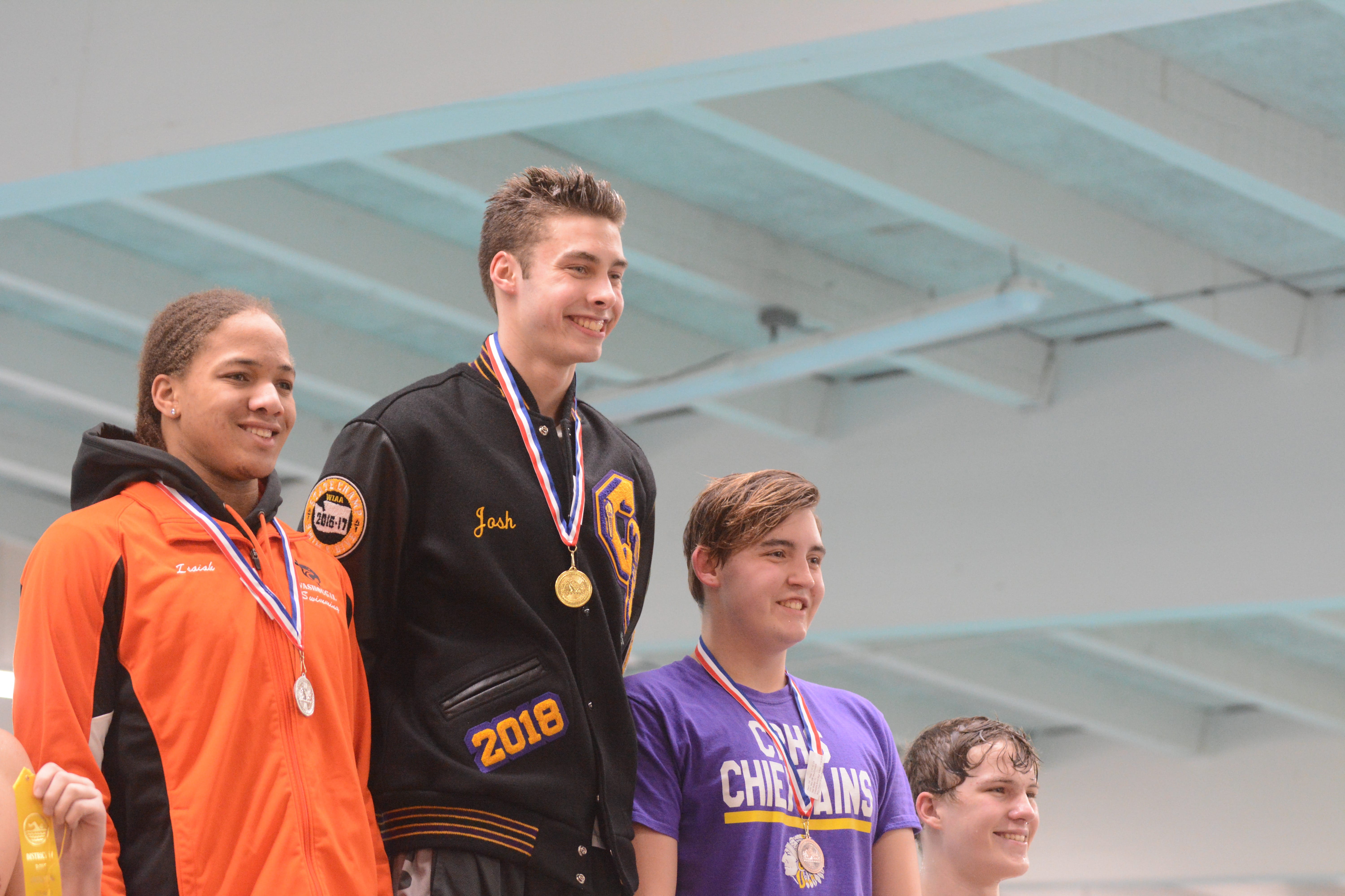 Columbia River's Josh Bottelberghe, center, Washougal's Isaiah Brown, left, and Columbia River's Sam Walker stand atop the awards podium after the 200 freestyle at the 2A District 4 swim championships Saturday at Mark Morris High School in Longview (Micah Rice/The Columbian)