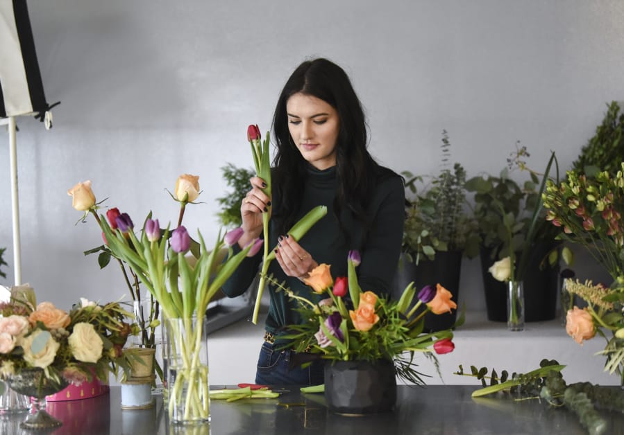 Kara Pyle, lead floral designer at Stem Floral Design in Vancouver, selects and prepares a flower for a customer’s arrangement.