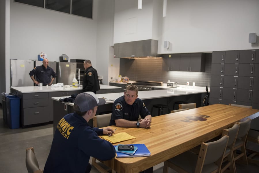 Vancouver Fire Department Capt. Scott Blanton, center, talks with his son Alex Blanton of Battle Ground, left, in the kitchen area at the new Vancouver Fire Station 2. Both stations feature massive kitchens with 24-foot ceilings to accommodate the large crews.
