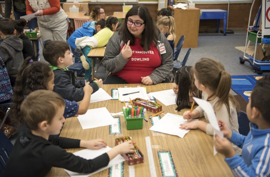 Fort Vancouver High School senior Alexandra Mayo helps kindergartners with a drawing and reading project Tuesday morning at Peter S. Ogden Elementary School. Mayo is in the high school’s Careers in Education program, learning the skills required to become a teacher.