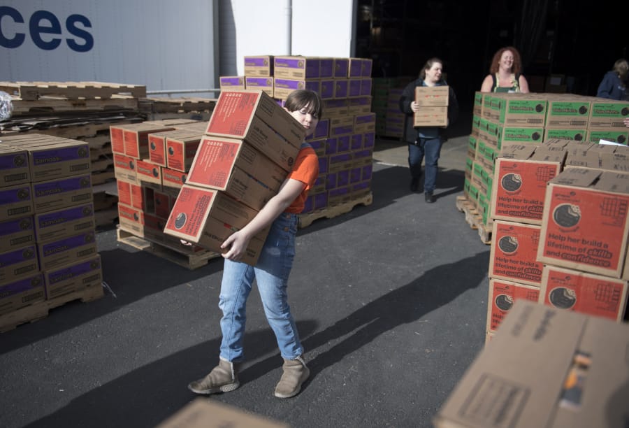Girl Scout troops from Southwest Washington and the Portland area gather for depot day, moving more than 500,000 boxes of cookies from a Vancouver warehouse into cars, trucks, horse trailers and U-Hauls. Kira Louvier, 11, of Vancouver helps move cookies into a van on Saturday.