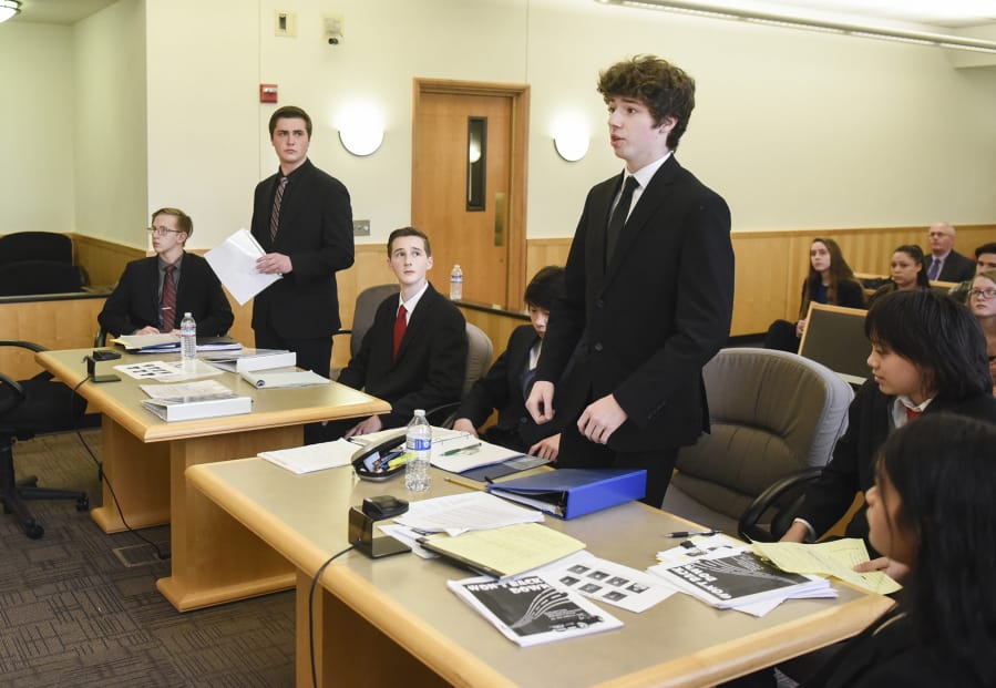 Cascadia Technical Academy students from left, Cameron Achziger, Justin Bates and David Guiher, listen as Camas High School freshman Hayden Devore, who acted as a lawyer for the defense, center, gives opening statements during a mock trial Thursday at the Clark County Courthouse.