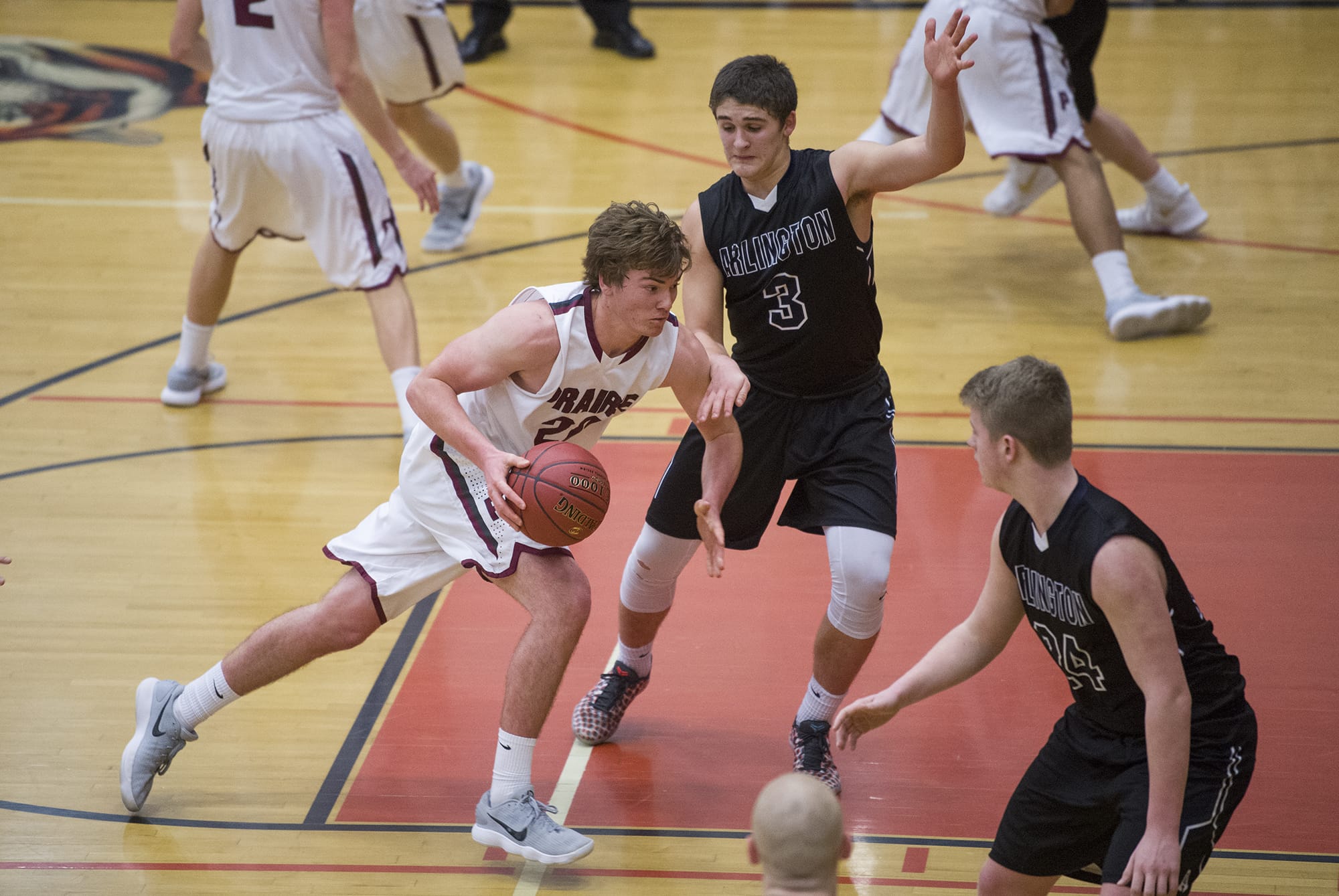 Prairie’s Logan Reed (20) pushes past Arlington’s Griffin Gardoski (3) and Joseph Schmidt (24) during the 3A regional boys basketball game at Battle Ground High School, Saturday February 24, 2018.
