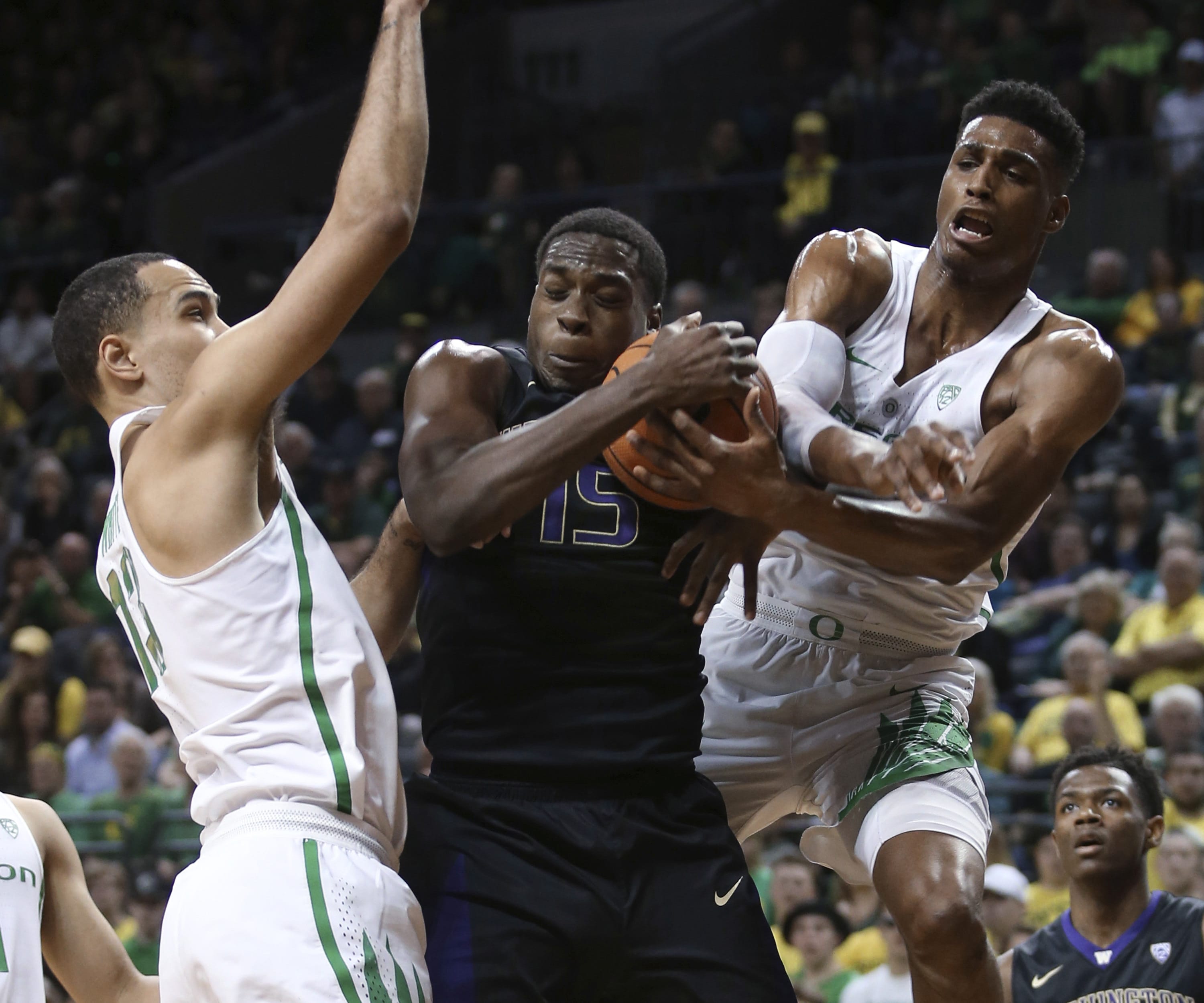 Oregon's Paul White, left, watches as temmate Kenny Wooten, right, works against Washington's Noah Dickerson for a rebound during the first half of an NCAA college basketball game Thursday, Feb. 8, 2018, in Eugene, Ore.
