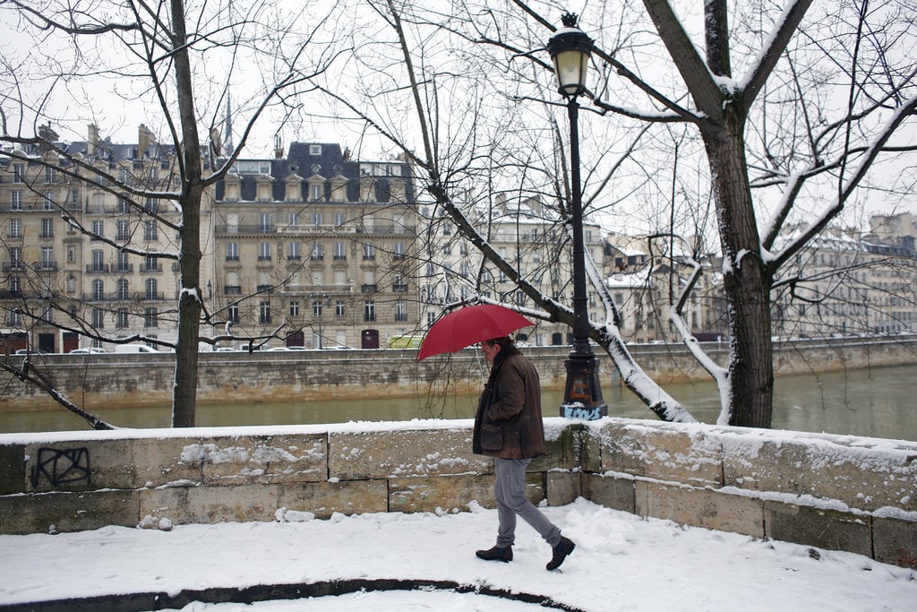 A man walks in a snowy street of Paris, Friday, Feb. 9, 2018. Authorities are telling drivers in the Paris region to stay home as snow and freezing rain have hit a swath of France ill-prepared for the wintry weather.