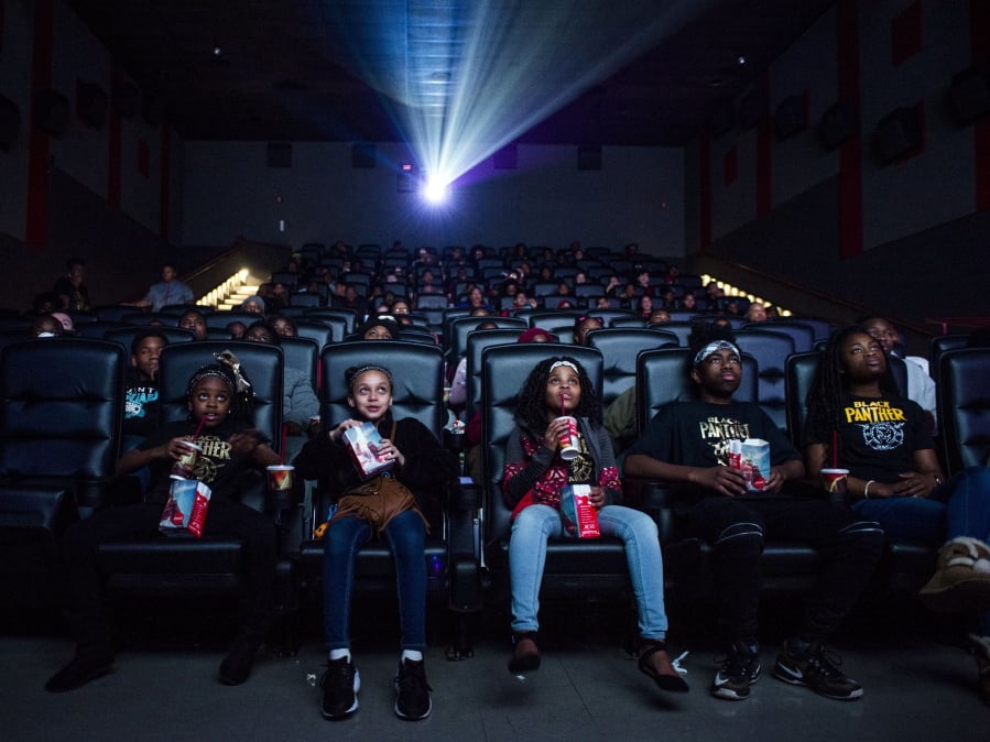 Mari Copeny, third from left, watches a free screening of the film “Black Panther” with more than 150 children, after she raised $16,000 to provide free tickets in an entire theater on Monday in Flint Township, Mich. As “Black Panther” debuts in theaters across the U.S., educators, philanthropist, celebrities and business owners are pulling together their resources to bring children of color to see the film that features a black superhero in a fictional, un-colonized African nation.