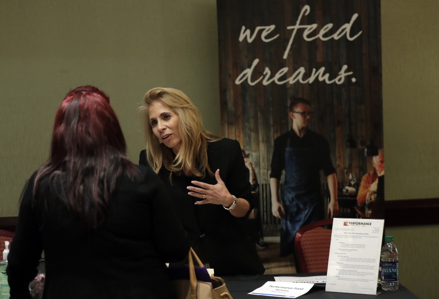 In this Tuesday, Jan. 30, 2018, photo, Grace Ochoa, of Performance Food Service, right, talks with a job applicant at a JobNewsUSA job fair in Miami Lakes, Fla. On Friday, Feb. 2, the U.S. government issues the January jobs report.