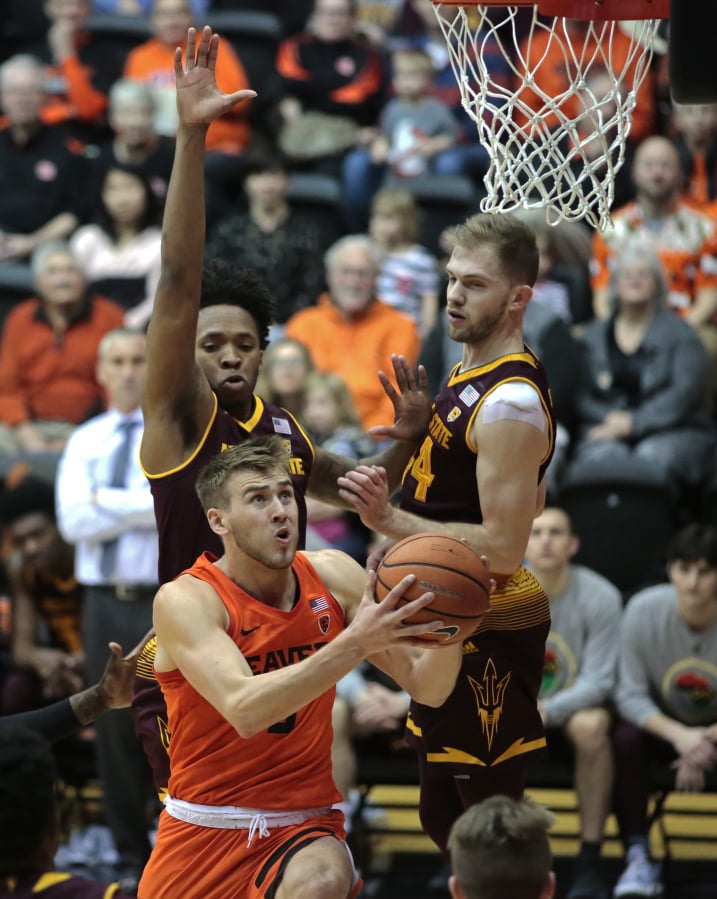 Oregon State’s Tres Tinkle, front, drives to the basket past Arizona State’s Kimani Lawrence, rear left, and Kodi Justice, rear right, in the first half of an NCAA college basketball game in Corvallis, Ore., Saturday, Feb. 24, 2018. (AP Photo/Timothy J.