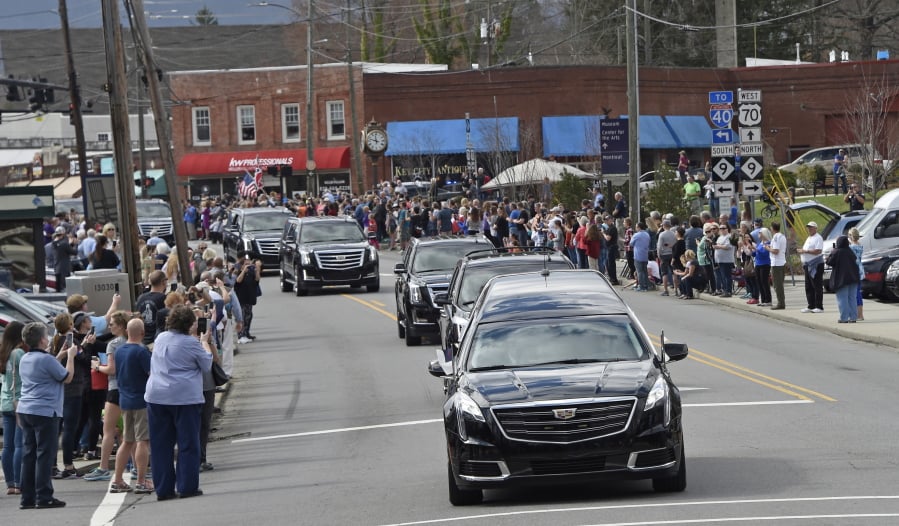 People line the street Saturday as the hearse carrying the body of the Rev. Billy Graham travels through Black Mountain, N.C.