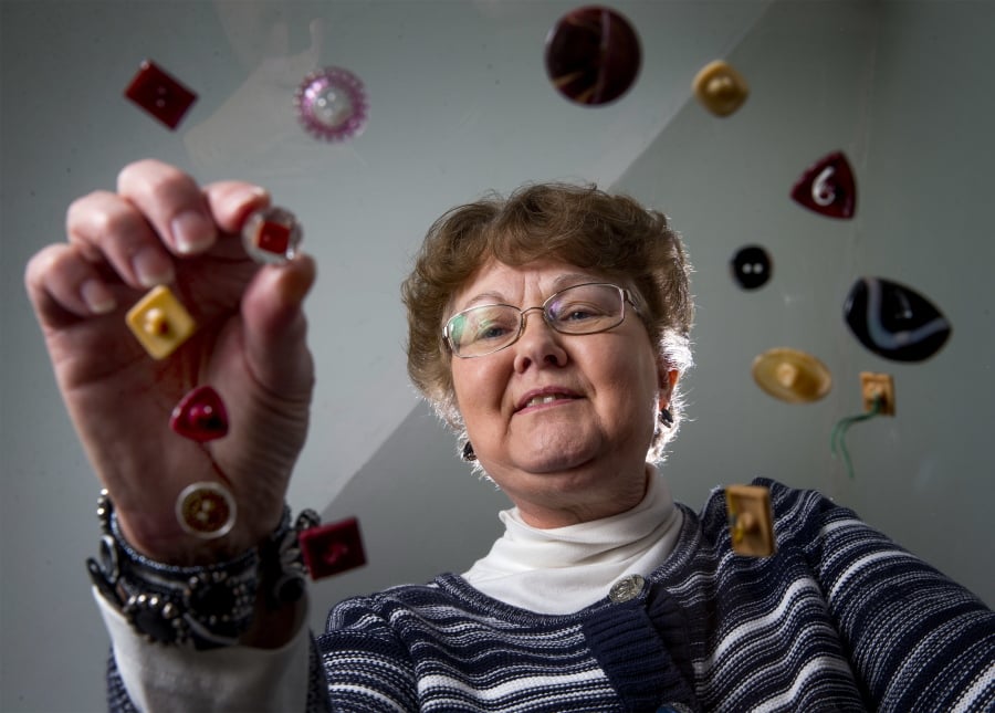 Sandi Olsen, president of the Eugene Button Club, looks at some of her button collection Jan. 23 at her home near Fall Creek, Ore.