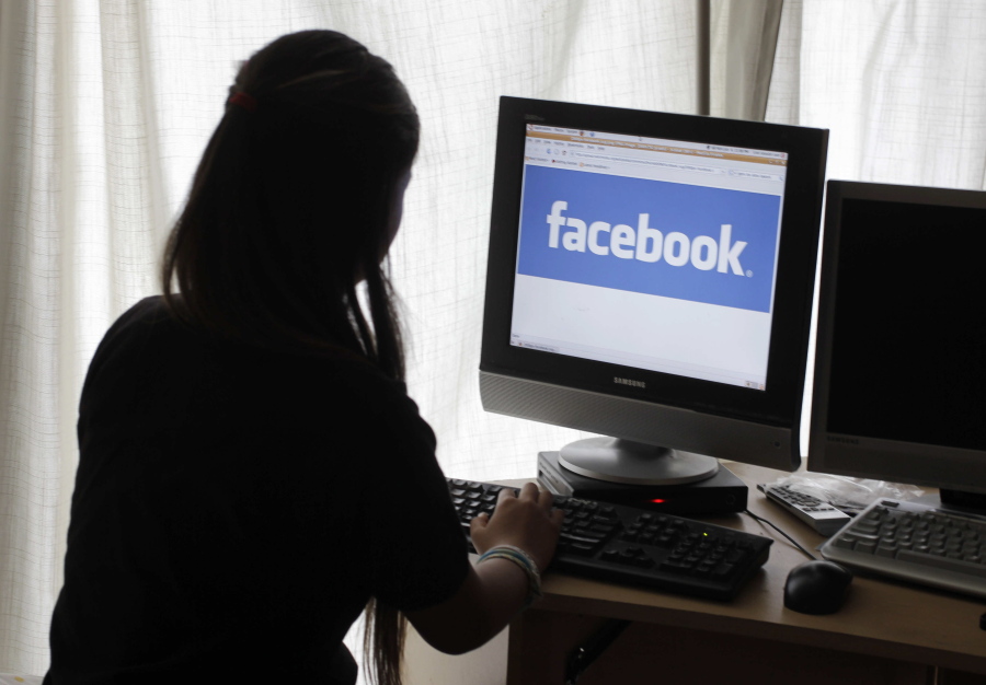 A girl looks at Facebook on her computer in Palo Alto, Calif. Baffled in 2016 by Russian agents who bought ads in an attempt to sway the U.S. presidential campaign, Facebook told the National Association of Secretaries of State on Saturday that the company would send postcards to potential buyers of political ads to confirm they reside in the U.S.