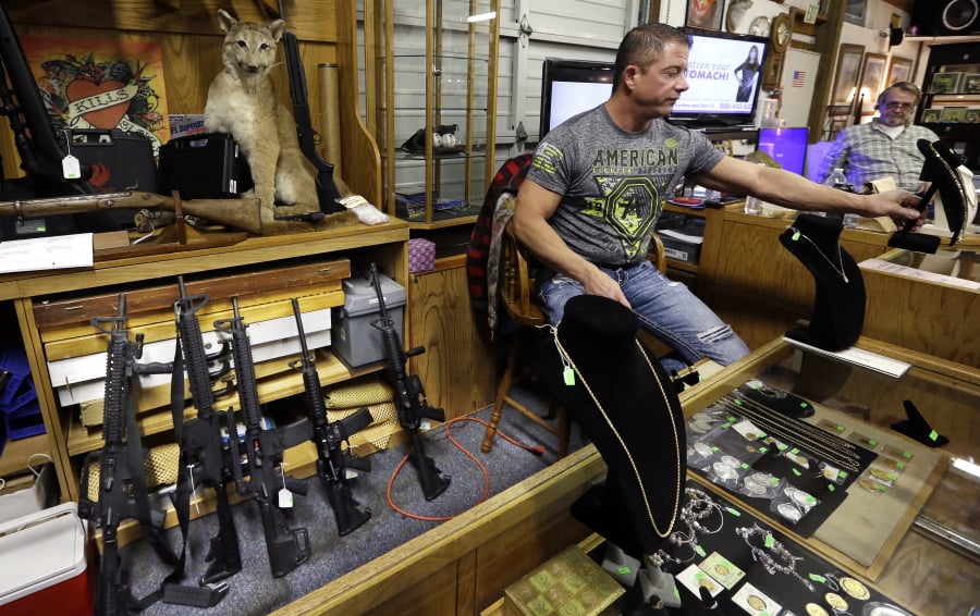 In this photo taken Oct. 20, 2017, Johnny’s Auction House owner John West prepares items, including a line of assault rifles behind, for auction where the company handles gun sales for both civilians and a half dozen police departments and the Lewis County Sheriff’s Office, in Rochester.