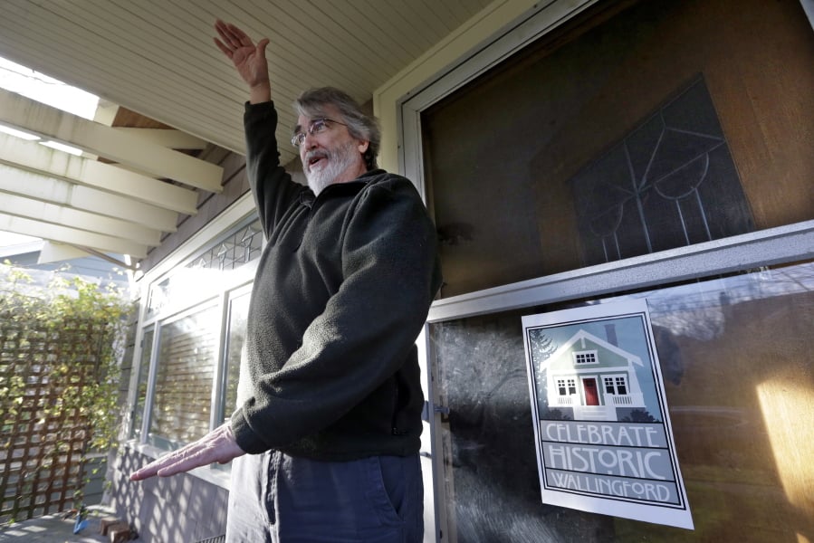 In this Dec. 13, 2017, photo, Greg Flood stands on the porch of his two-story home and talks about a proposal to allow houses to be built three-to-five stories high on his street, now dotted with bungalows and stately Craftsman homes, in Seattle. As a solution to a massive influx of new residents and an ensuing housing crunch, city officials are proposing to let developers build taller and denser in core areas across the city and require them to either include units that working-class people can afford, or pay for projects to be built elsewhere.