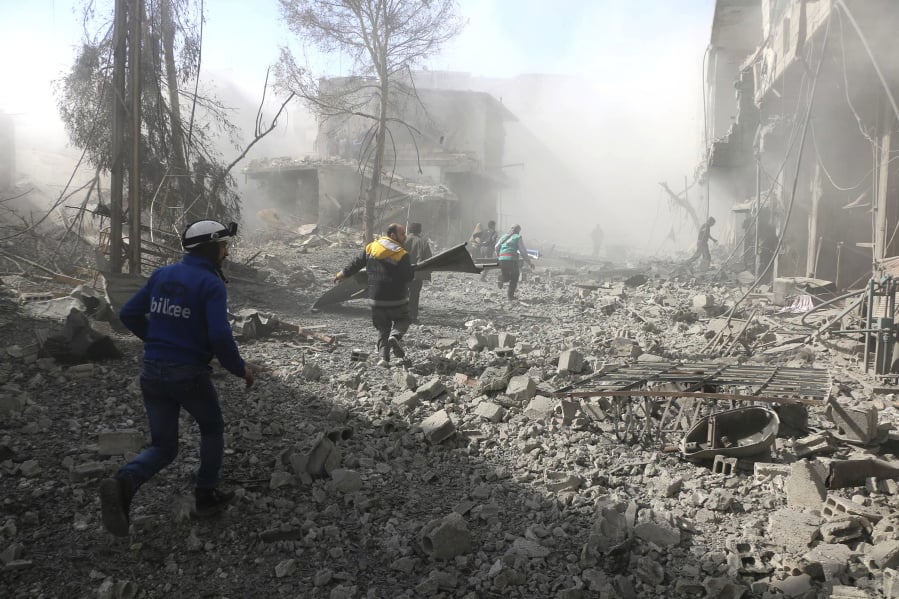 Members of the Syrian Civil Defense run to help people in a street that was hit by airstrikes and shelling in Ghouta, Syria.