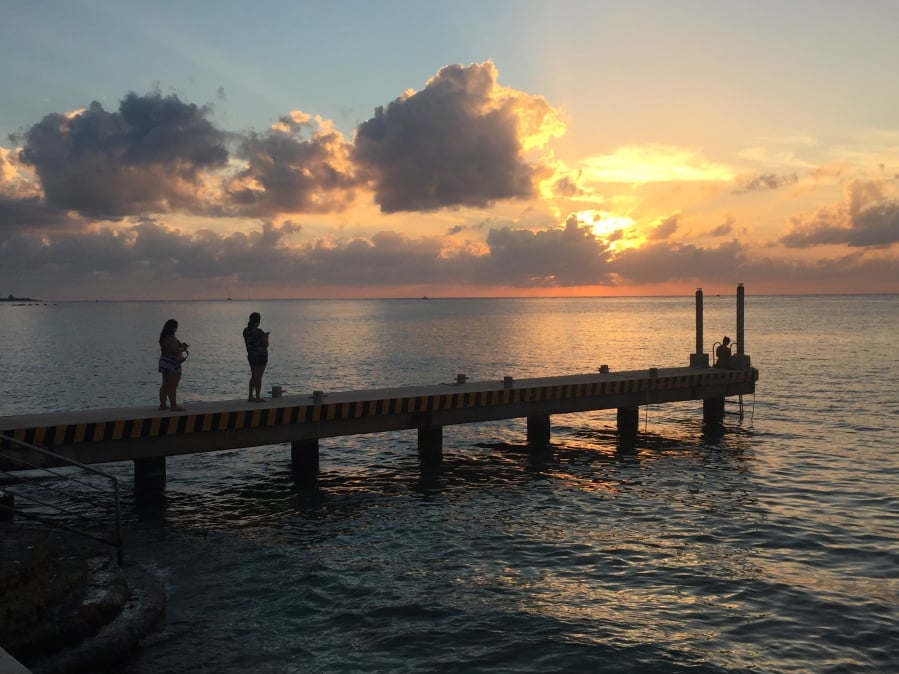 People watch the sun set over the Caribbean on Dec. 22 on a pier in Cozumel, Mexico. Mexico is a popular vacation destination for winter and spring. But big decisions await travelers, especially those uninterested in the all-inclusive resorts that Cancun is known for.