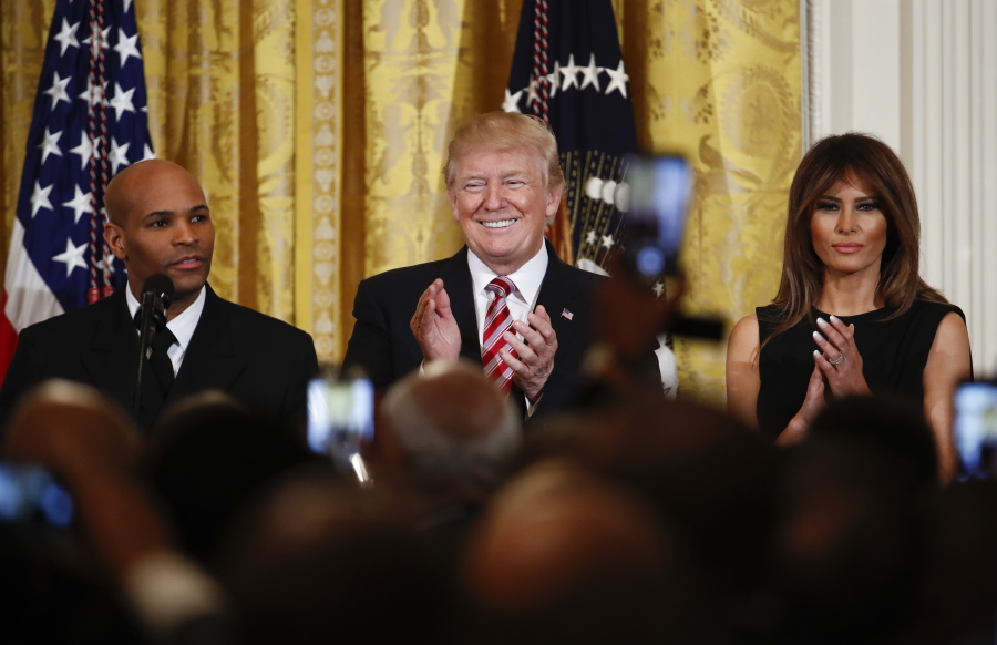 President Donald Trump, center, and first lady Melania Trump applaud as Surgeon General Jerome Adams speaks during the National African American History Month reception Tuesday in the East Room of the White House.