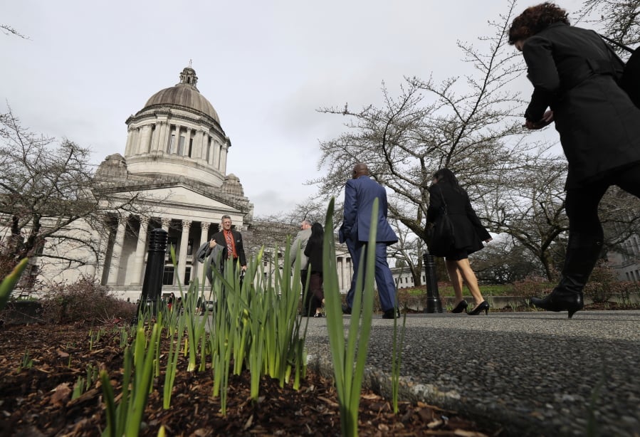 Spring daffodils are shown emerging from the ground, Wednesday, Feb. 7, 2018, at the Capitol in Olympia, Wash., as pedestrians walk on a sidewalk leading to the Legislative Building during the 2018 regular session of the Washington State Legislature. (AP Photo/Ted S.