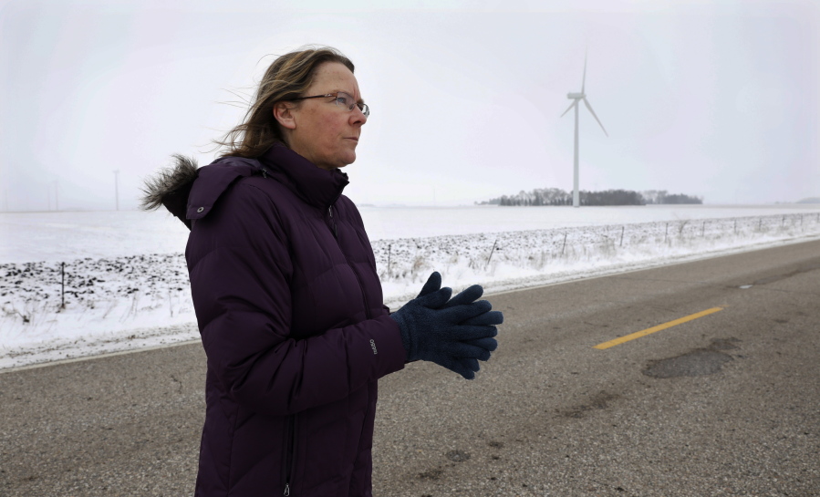 Dorenne Hansen, of Glenville, Minn., stands on a rural highway near a wind turbine in a field on Wednesday near Northwood, Iowa. Opponents of wind power are successfully stalling or rejecting wind-farm projects across the country. Criticism of wind turbines is nothing new, but this latest rebellion is raising a host of issues and halting developments.