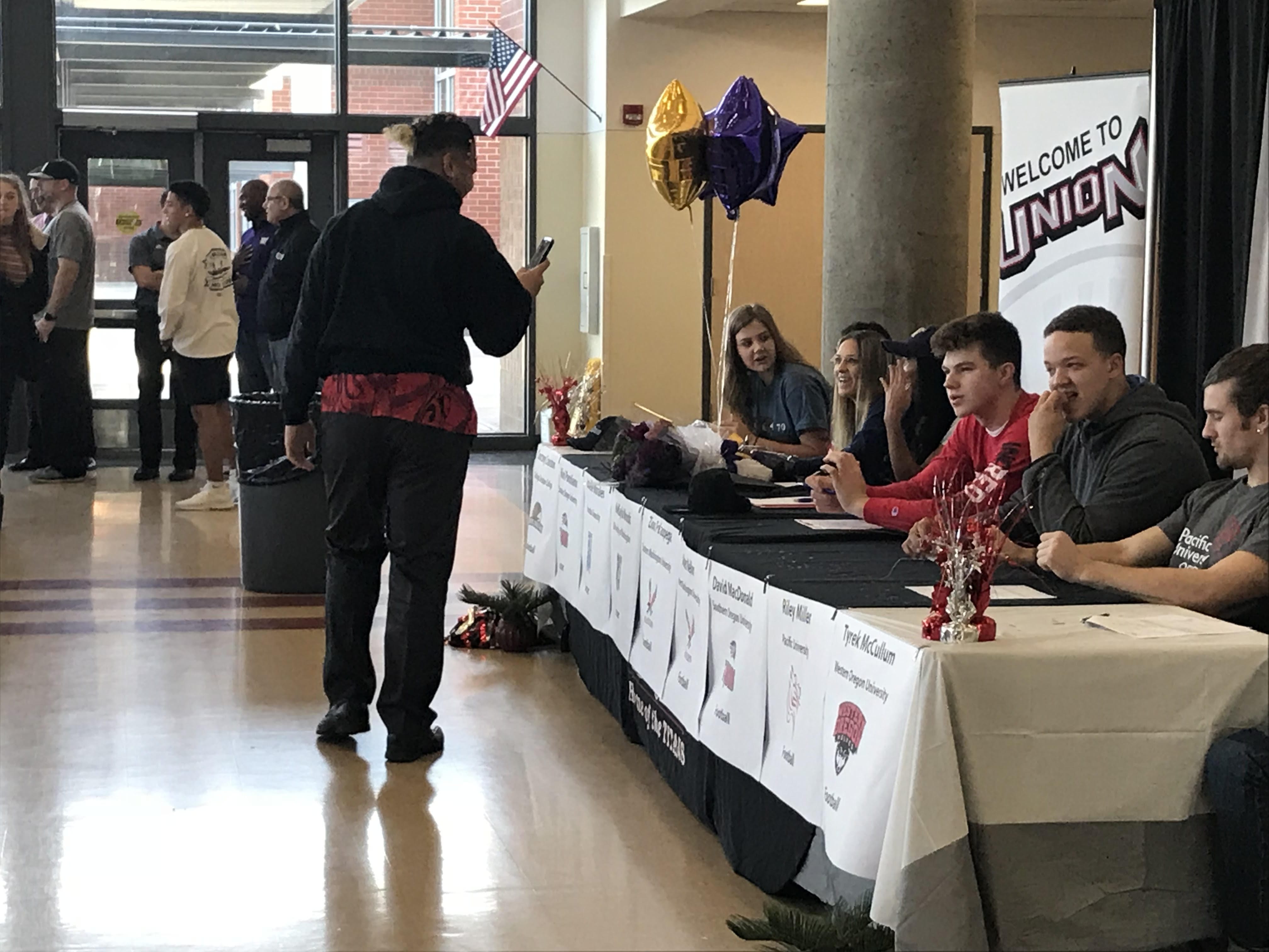 Union senior Zion Fa'aopega (left) captures the Signing Day festivities on his smartphone before the high school's ceremony began Wednesday morning. Fa'aopega and Aiden Nellor signed to play football at Eastern Washington, two of the Titans' five college-bound football players.