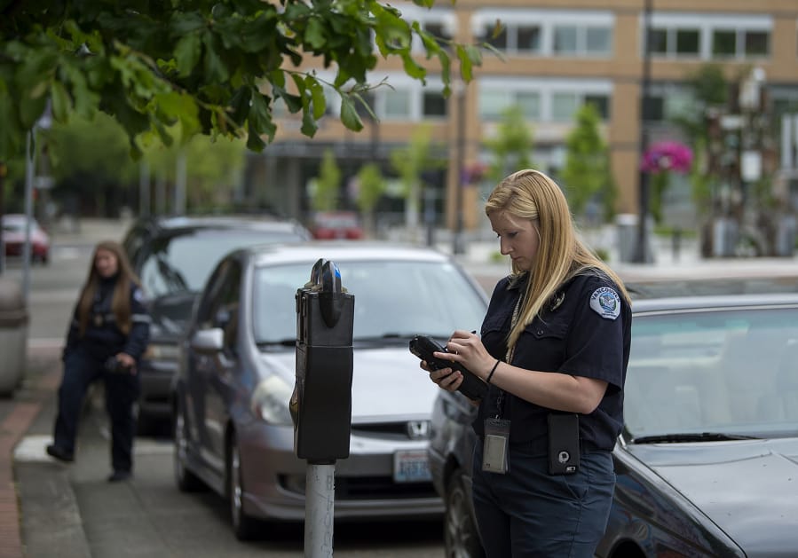 Parking enforcement officer Holly Naramore issues a ticket for an expired meter in downtown Vancouver in 2017. The city is now talking about increasing parking rates and developing demand-based fees.