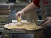 A Papa Murphy’s worker in Vancouver sprinkles cheese while creating a pizza. The Vancouver-headquartered company is hoping delivery and online ordering can help return it to profitability.
