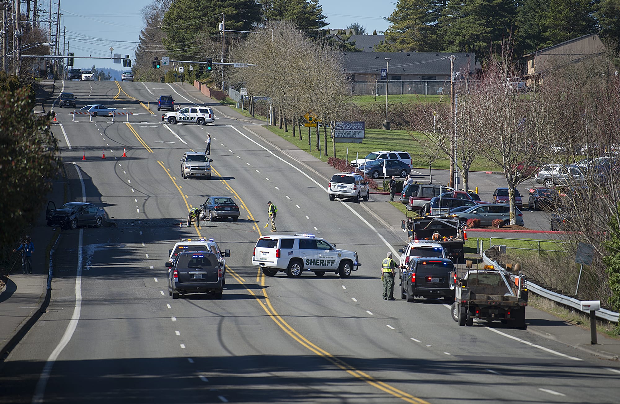Officials investigate a two-car collision involving a Volkswagen Jetta, left, and a Subaru Legacy, center, near Columbia River High School on Tuesday morning, March 6, 2018. One person was confirmed dead in the crash and police route traffic around the scene on 99th Street.