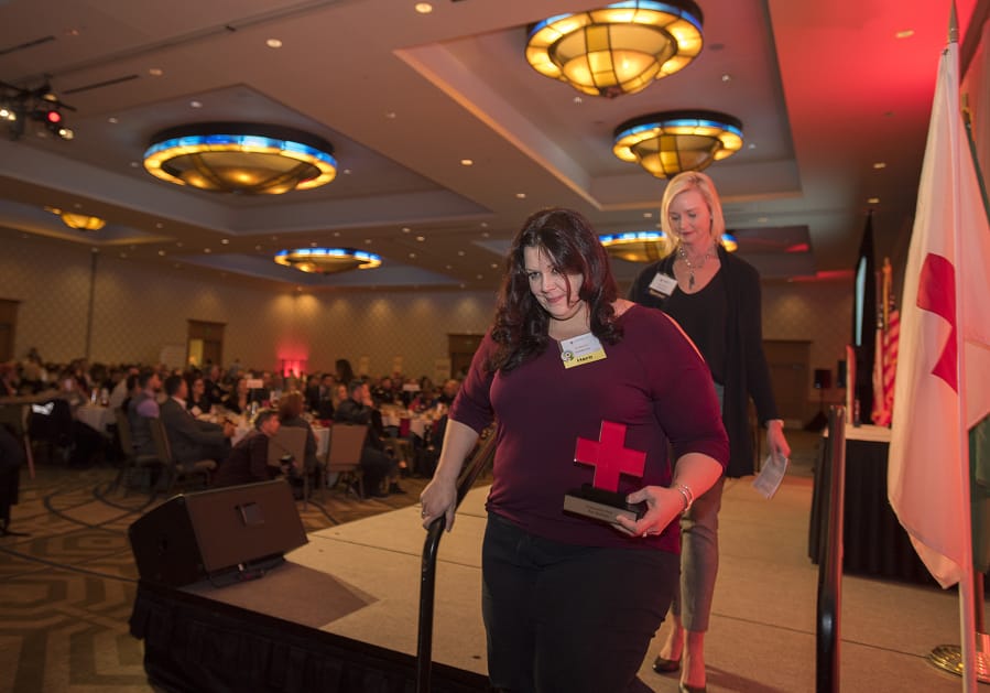 Community Hero award recipient Kim Mosiman, front, exits the stage after accepting her award from Kelly Schrader of IQ Credit Union during the American Red Cross 21st annual Hero Awards Breakfast at the Hilton Vancouver Washington on Friday morning.