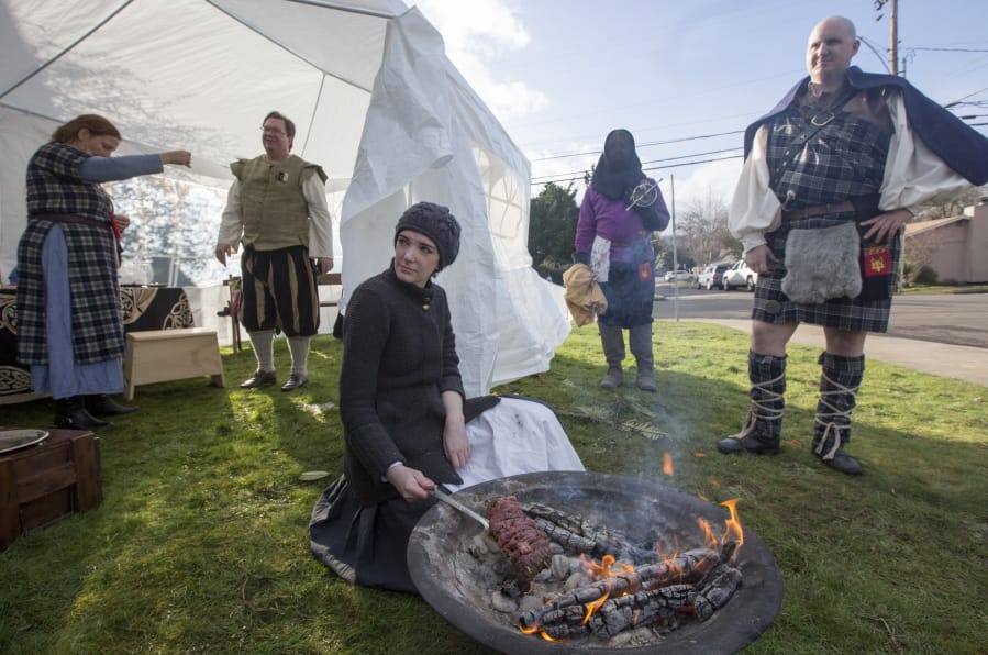 Lady Anneke von Frankenstein, aka Jessica Hagen, roasts meat on the fire she started herself while other Stromgardians hang around outside the Camas Community Center. Hagen went on to win the arts and sciences tournament.
