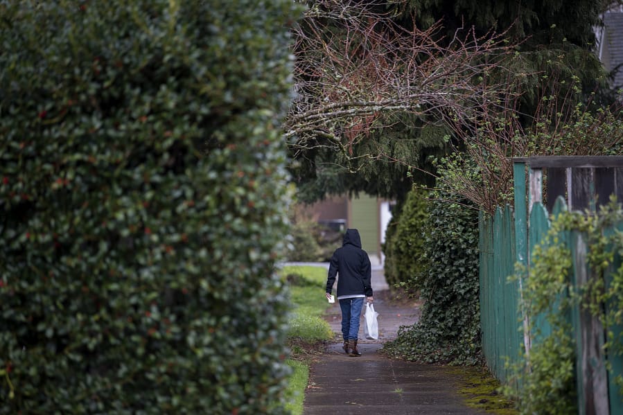 A pedestrian strolls through the rain along tree-lined streets in the Hough neighborhood March 13.