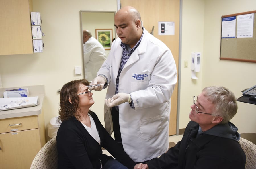 Neurologist Gurjeet Singh injects Botox into Kari Carlson’s forehead as her husband, Keith Carlson, offers his support. Carlson receives 31 Botox injections every 12 weeks to manage her chronic migraines.