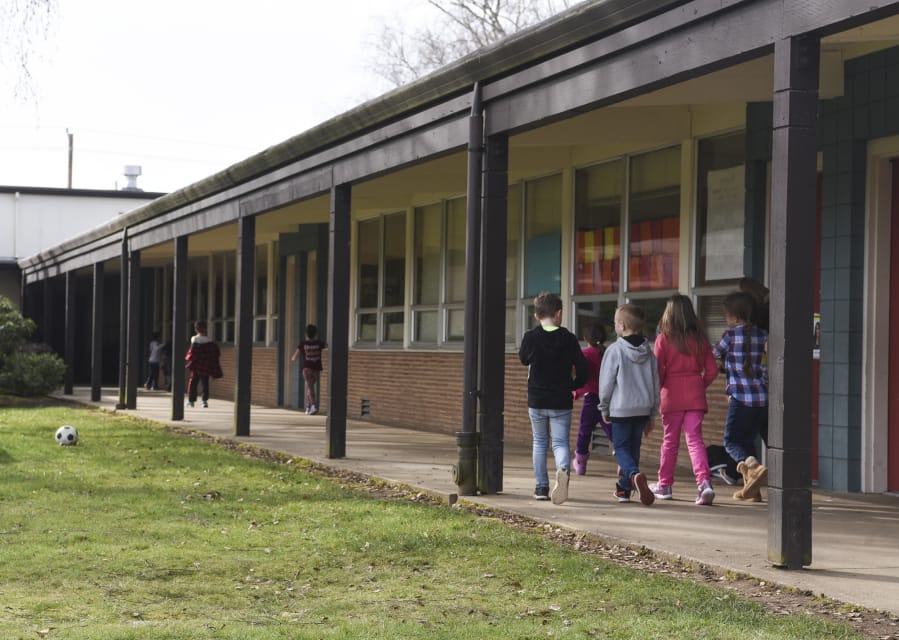 Students at Glenwood Heights Primary School walk down a covered walkway to a classroom Wednesday. The school, which was built in 1956, has many outdoor classroom entrances, which Battle Ground Public Schools says poses a safety concern. The district is seeking approval of a $224.9 million bond issue in an April 24 special election.