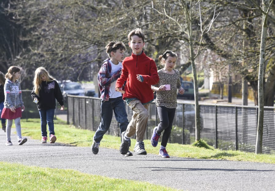 Third-graders Avery Ahrens, from left, Sam Coté and Karina Woodley run laps around the playground at Hough Elementary School. The trio are among the regular participants in the new Hough Mileage Club — a voluntary running program offered during lunch recesses.