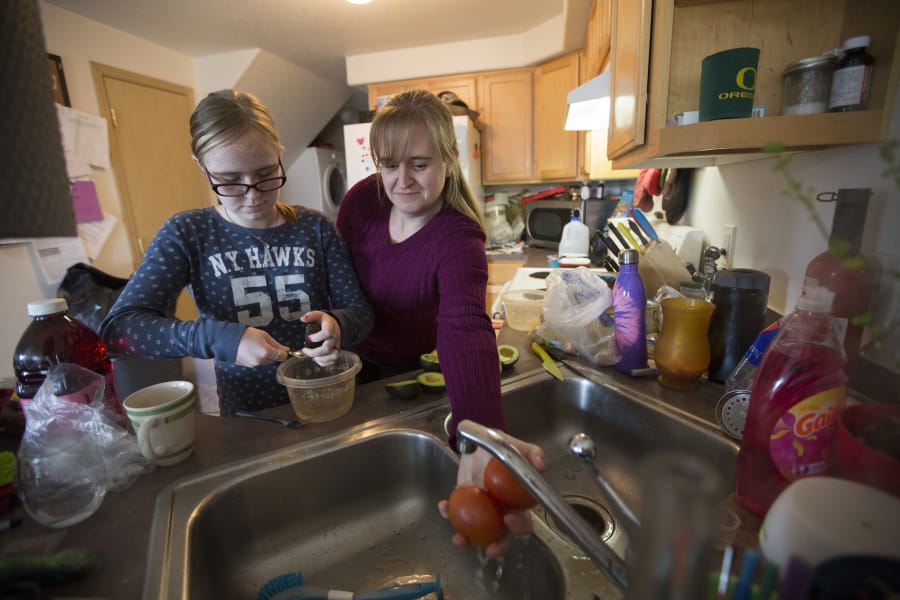Jennifer Waller, right, prepares guacamole with daughter Kayla, 13, at their Battle Ground home. The family earns just below the median wage in Clark County but relies heavily on government programs such as food stamps and Women, Infants and Children to pay for groceries.