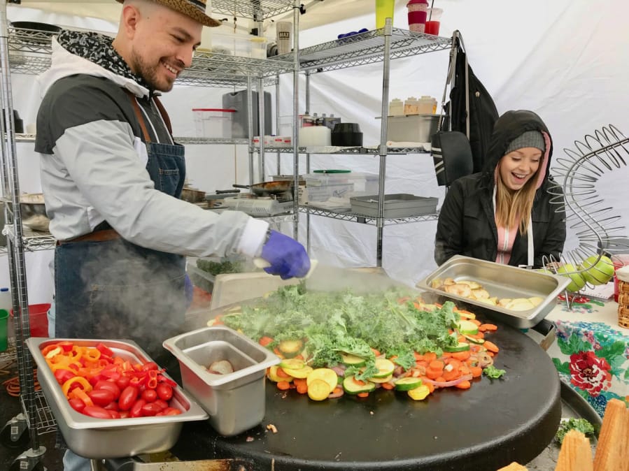 Junior Estrada, owner of NW Grill Farm-to-Fork, entertains Megan Ashley while heating vegetables.
