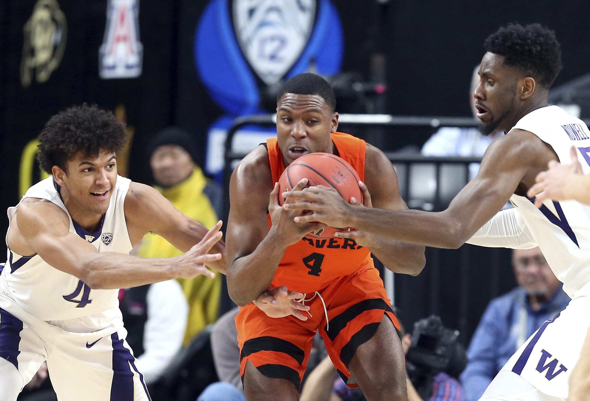 Washington's Matisse Thybulle, left, and Jaylen Nowell, right, and Oregon State's Alfred Hollins reach for a loose ball during the first half of an NCAA college basketball game in the first round of the Pac-12 men's tournament Wednesday, March 7, 2018, in Las Vegas.