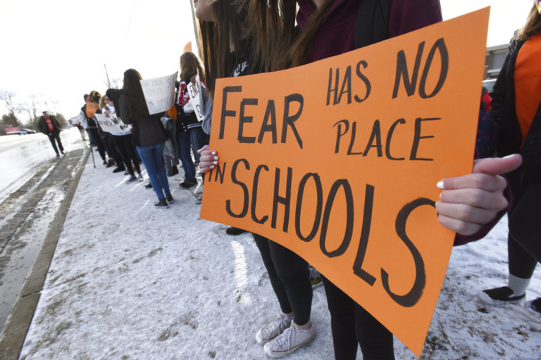 Students hold signs as they participate in a walkout to protest gun violence, Wednesday, March 14, 2018, at Lakeshore High School in Stevensville, Mich., one month after the deadly shooting inside a high school in Parkland, Fla.