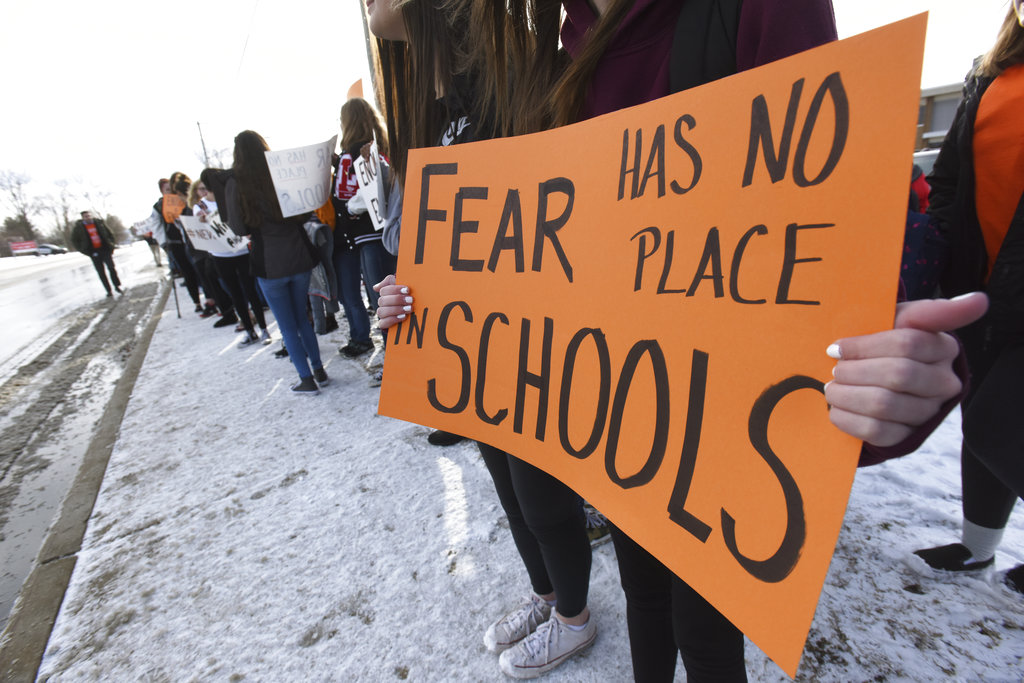 Students hold signs as they participate in a walkout to protest gun violence, Wednesday, March 14, 2018, at Lakeshore High School in Stevensville, Mich., one month after the deadly shooting inside a high school in Parkland, Fla.