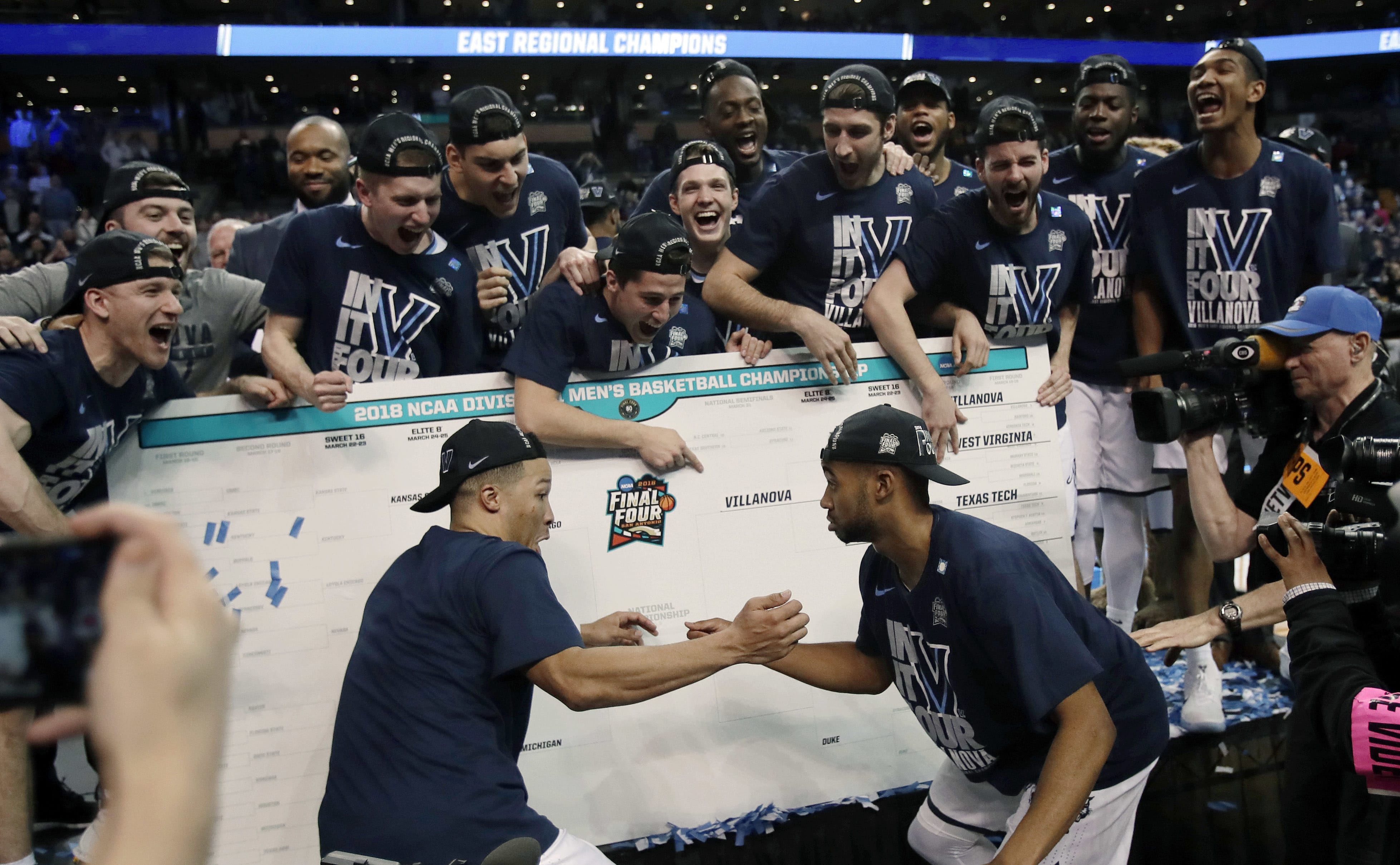 Villanova's Jalen Brunson, left, and Phil Booth, right, celebrate with teammates after affixing the team name on the bracket after beating Texas Tech in an NCAA men's college basketball tournament regional final, Sunday, March 25, 2018, in Boston. Villanova won 71-59 to advance to the Final Four.