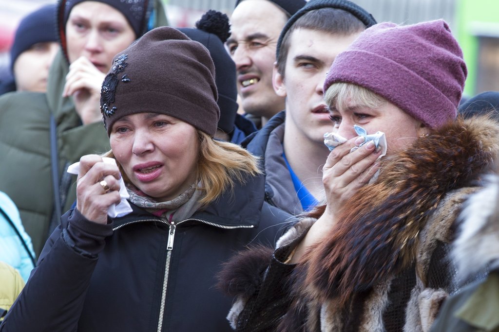 People react after laying flowers for the victims of a fire in a multi-story shopping center in the Siberian city of Kemerovo, about 3,000 kilometers (1,900 miles) east of Moscow, Russia, Monday, March 26, 2018. Russian officials say a fire at a shopping mall in a Siberian city has killed over 50 people. The Ekho Mosvky radio station quoted witnesses who said the fire alarm did not go off and that the staff in the mall in Kemerovo did not organize the evacuation.