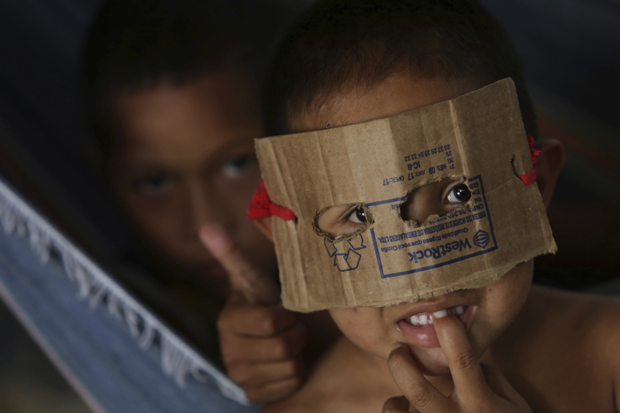 A Warao boy from Venezuela dons a mask fashioned from cardboard at a a shelter in Pacaraima, the main entry point for Venezuelans in the Brazilian state of Roraima. Opened late last year with the capacity to house about 250 people, the shelter, a former warehouse, today has upwards of 500, and more are arriving daily.