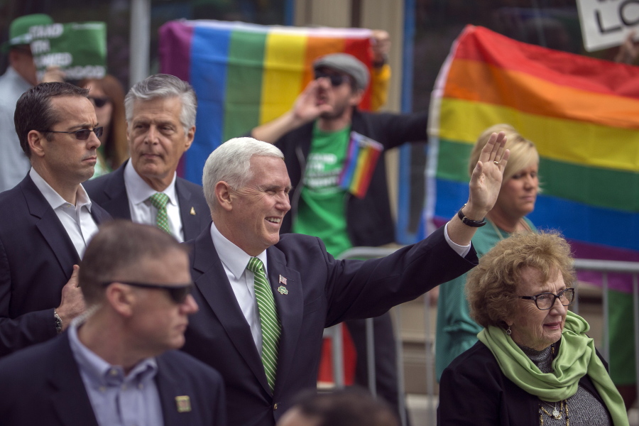 Vice President Mike Pence and his mother Nancy Pence Fritsch, right, wave while walking in the St. Patrick's Day parade Saturday, March 17, 2018, in Savannah, Ga. Crowds behind barricades across the street cheered and chanted "U-S-A" as Pence waved and gave a thumbs up sign. There were also a few protesters who followed Pence throughout the parade. (AP Photo/Stephen B.