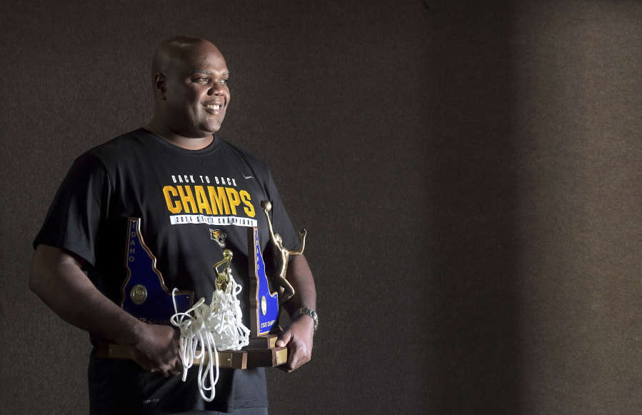 Coach Marsell Colbert holds state championship trophies March 9 in Post Falls, Idaho.